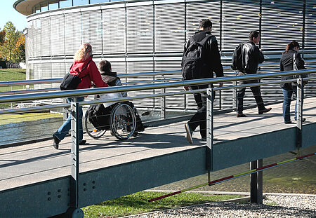 Das Bild zeigt fünf Personen auf einer Brücke, vier Personen zu Fuß und eine Person im Rollstuhl. Bildnachweis: Foto: OTH Regensburg Das Bild zeigt fünf Personen auf einer Brücke, vier Personen zu Fuß und eine Person im Rollstuhl. Bildnachweis: Foto: OTH Regensburg